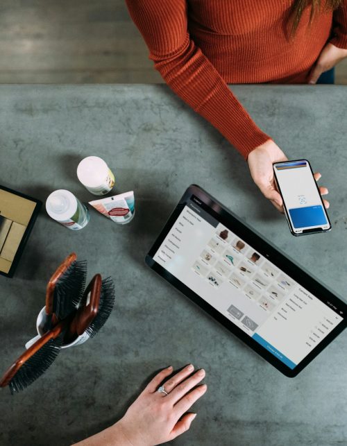 person holding smartphone beside tablet computer